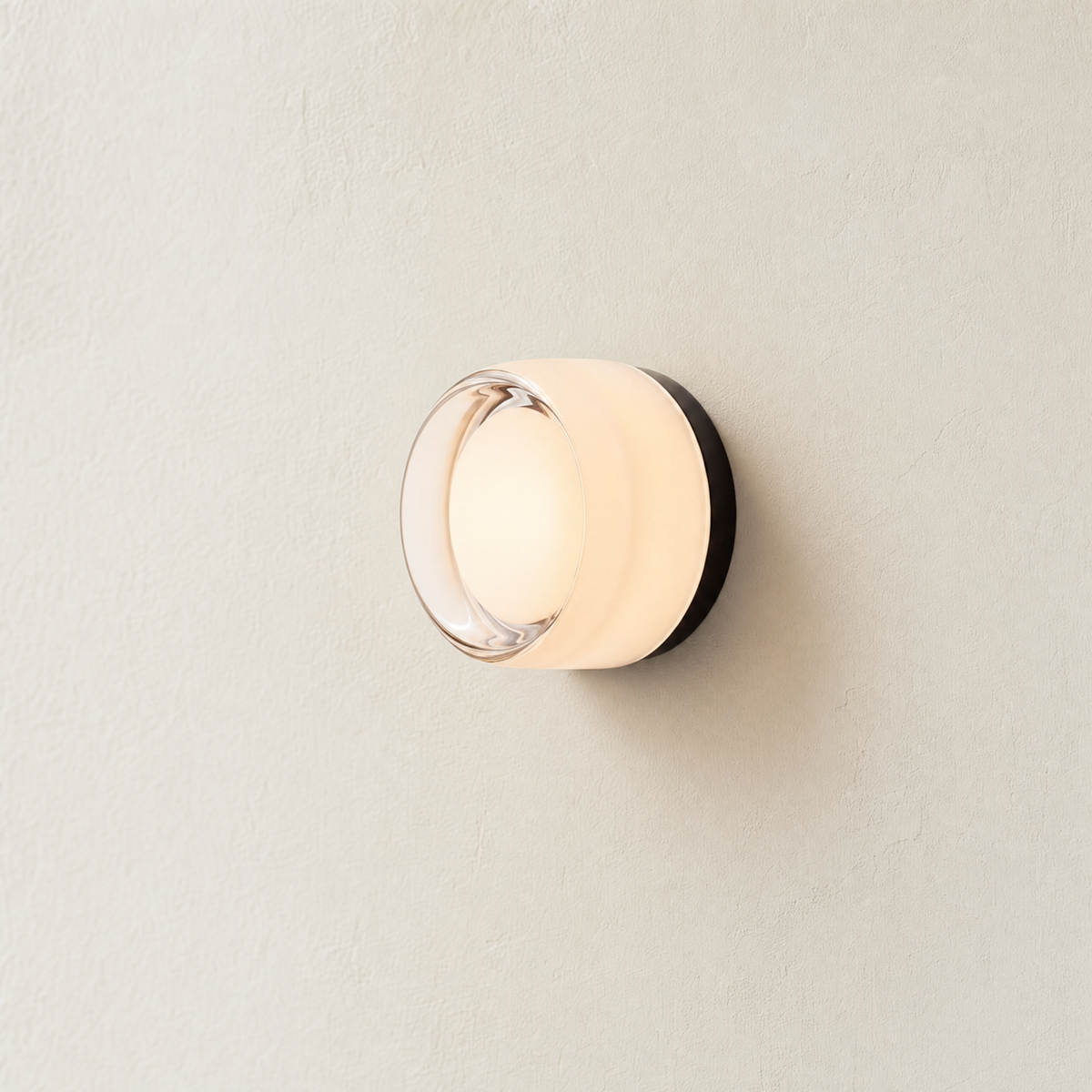 Ansa wall sconce in White art glass, lit on a cream plaster wall