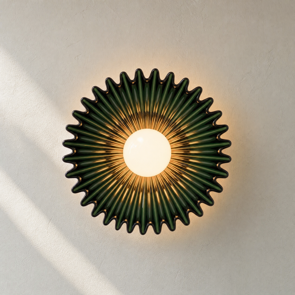 Calla ceramic wall sconce in Green glaze, lit on a cream wall